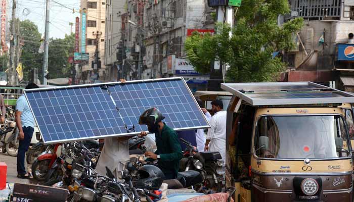 A man carries a solar plate in a local market, Karachi. — PPI/File