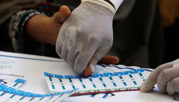 A medical worker helps a woman to draw blood for a HIV test at the free medical camp in Ratodero, Pakistan. — Reuters