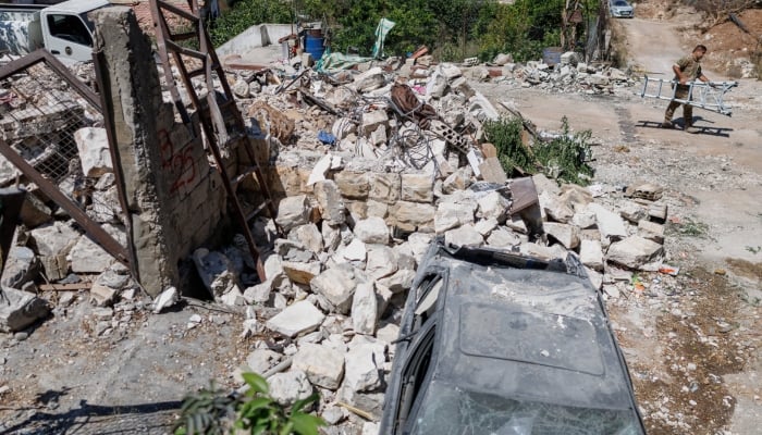 A Lebanese army officer carrying a ladder walks past a house damaged in an Israeli strike in Zawtar al-Gharbiyeh, a village in southern Lebanon, as Lebanese soldiers deploy in one of three so-called pilot zones following the withdrawal of Israeli forces under a US-brokered plan, July 27, 2026. — Reuters