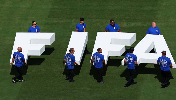 Pitch staff carry the Fifa logo on the pitch before the match. — Reuters