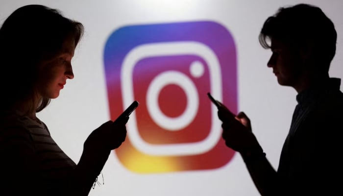 Teenagers pose for a photo while holding smartphones in front of an Instagram logo in this illustration created on September 11, 2025. — Reuters