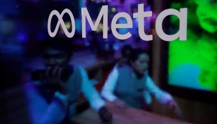 People are seen behind a logo of Meta Platforms, during a conference in Mumbai, India, September 20, 2023. — Reuters