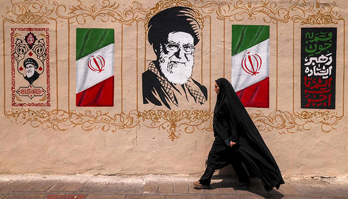 A woman walks past a mural depicting Irans late supreme leader Ali Khamenei at Valiasr Square in central Tehran on August 8, 2026. — AFP