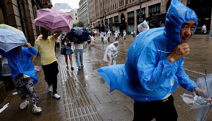 People use umbrellas and raincoats as winds intensify ahead of the arrival of Typhoon Dolphin in Shanghai, China, August 9, 2026. — Reuters