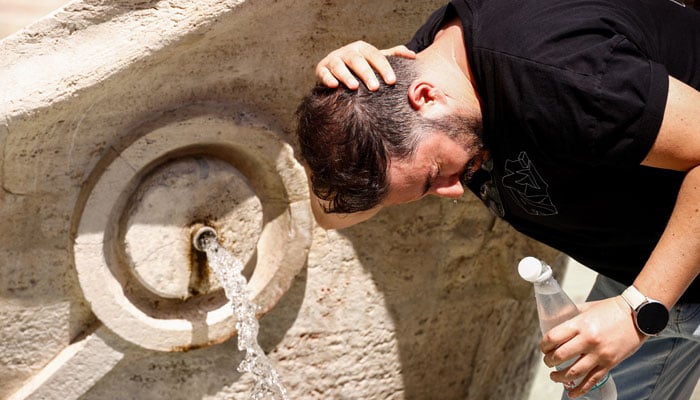 A man cools himself with water from the Fontana della Barcaccia during a heatwave in Rome, Italy, August 6, 2026.— Reuters