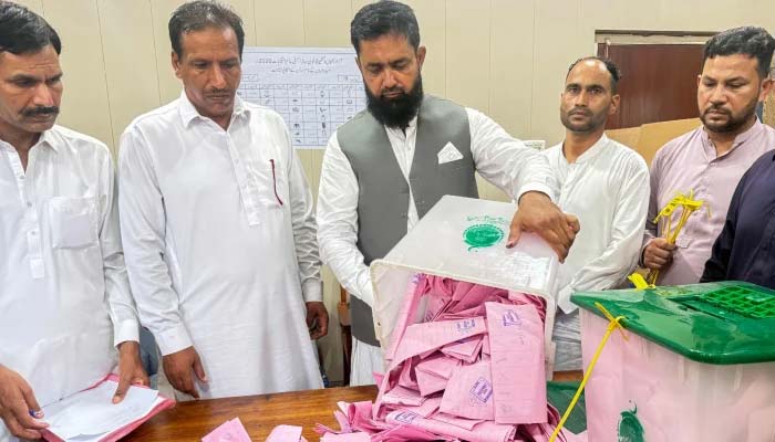A polling officer opens a ballot box for counting at a polling station in AJK on July 27, 2026. — AFP