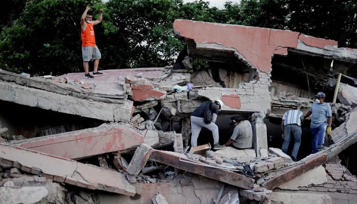 A rescue worker raises his fists to call for silence to locate victims under the rubble at the site of a collapsed building following an earthquake, in Cali, Colombia, August 10, 2026.— Reuters