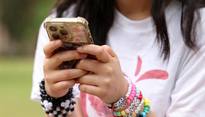 A girl poses holding her phone in an undated picture. — Reuters