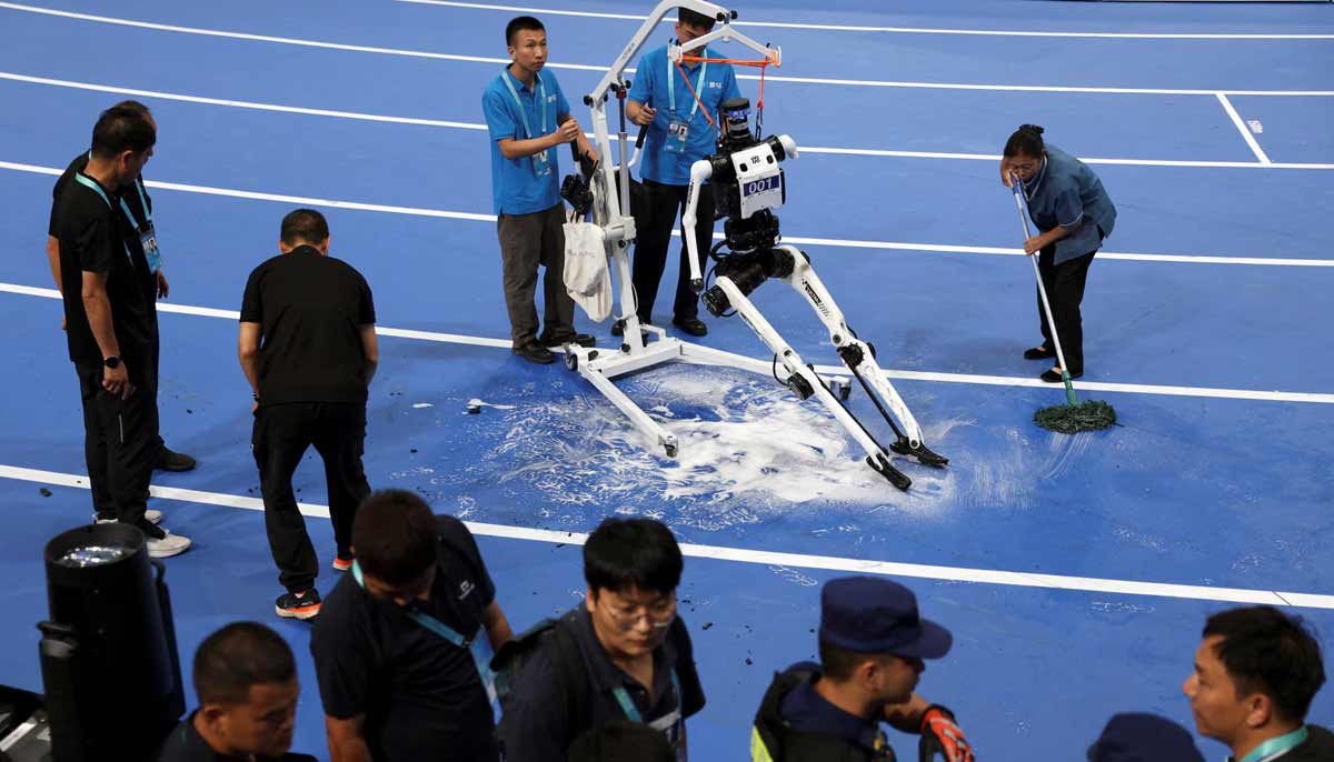 A staff member wipes the floor after fire extinguishers were used to put out the flame on a humanoid robot that caught fire after completing a 100m large-size group preliminary race, during the second World Humanoid Robot Games at the National Speed Skating Oval in Beijing, China, on August 22.— Reuters