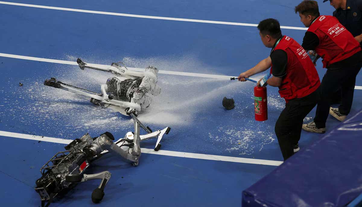 Staff members and a firefighter extinguish the flame on a humanoid robot that caught fire after completing a 100m large-size group preliminary race, during the second World Humanoid Robot Games at the National Speed Skating Oval in Beijing, China, on August 22.— Reuters