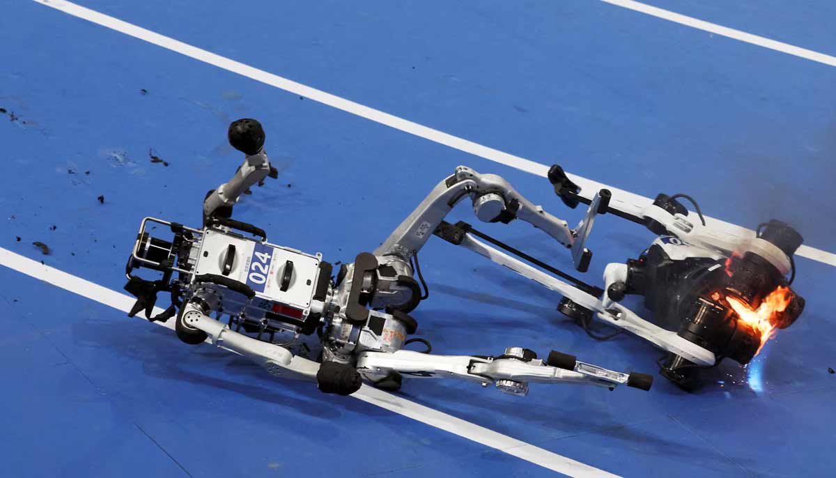 A humanoid robot falls next to another humanoid robot on fire after completing a 100m large-size group preliminary race, during the second World Humanoid Robot Games at the National Speed Skating Oval in Beijing, China, on August 22.— Reuters