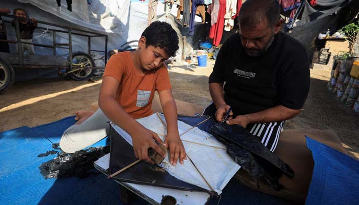 Palestinians make a kite at a tent camp sheltering displaced people in Gaza City, August 25, 2026. — Reuters