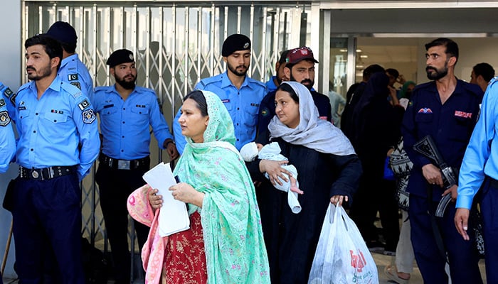 A woman carrying an infant moves past police officers as she leaves a ward following a deadly fire at the Pakistan Institute of Medical Sciences (PIMS) hospital in Islamabad, August 26, 2026. — Reuters