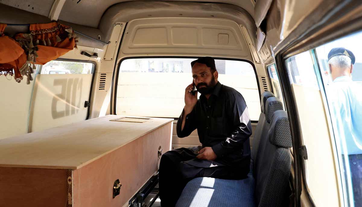 A man speaks on this mobile phone next to a coffin containing the body of a newborn victim inside an ambulance following a deadly fire at the Pakistan Institute of Medical Sciences (PIMS) hospital in Islamabad, Pakistan, August 26, 2026.— Reuters