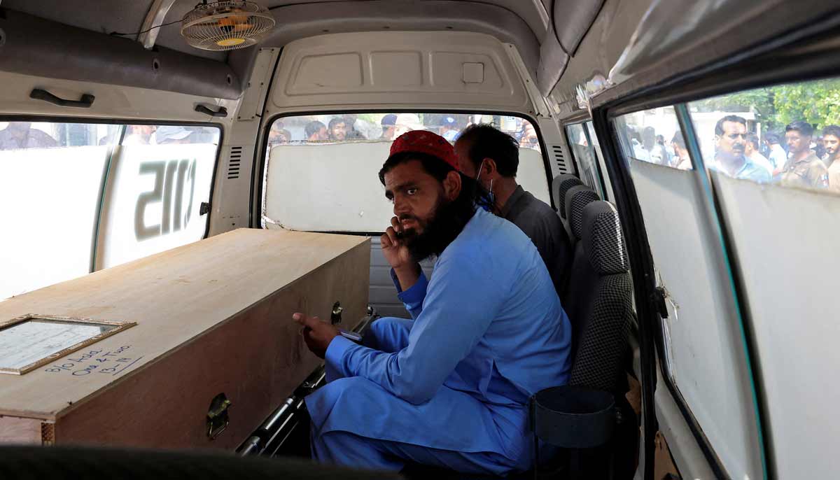 A man speaks on a mobile phone next to a coffin containing the body of newborn victim inside an ambulance following a deadly fire at the Pakistan Institute of Medical Sciences (PIMS) hospital in Islamabad, Pakistan, August 26, 2026.— Reuters
