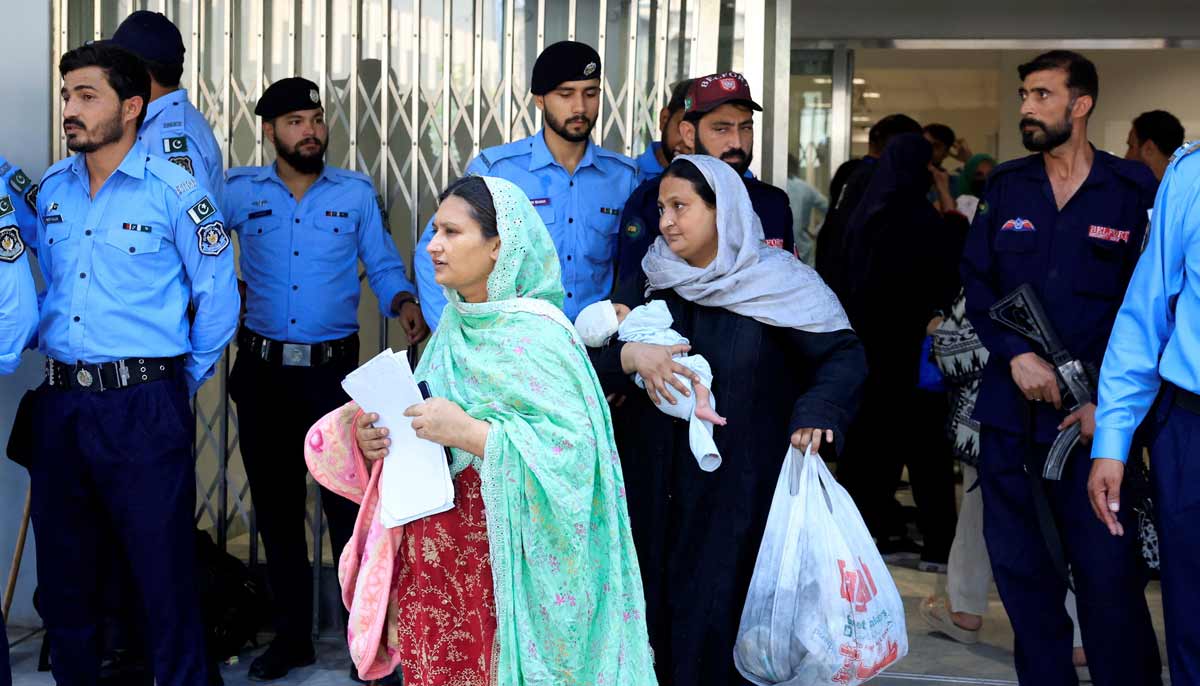 A woman carrying an infant moves past police officers as she leaves a ward following a deadly fire at the Pakistan Institute of Medical Sciences (PIMS) hospital in Islamabad, Pakistan, August 26, 2026.— Reuters
