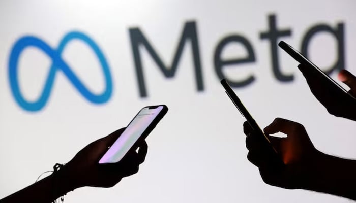 Teenagers pose for a photo while holding smartphones in front of a Meta logo in this illustration taken September 11, 2025. — Reuters