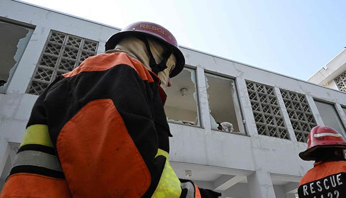 Rescuers walk past shattered windows at the scene following a fire outside Pims Hospital in Islamabad on August 26, 2026. — AFP