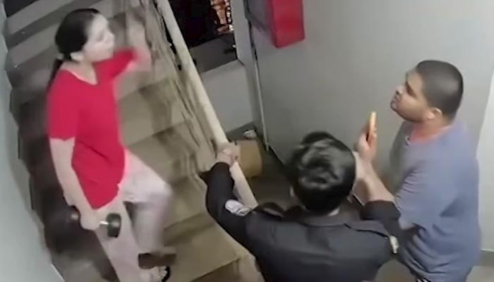 A woman with a dumbbell can be seen arguing with a man while a policeman can also be seen during the scuffle in Defence Housing Authority, Karachi. — Screengrab via CCTV/Geo News