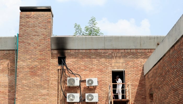 A man speaks on his mobile phone at the intensive care unit building with smoke marks, a day after a deadly fire at the Pakistan Institute of Medical Sciences hospital in Islamabad, August 27, 2026. — Reuters