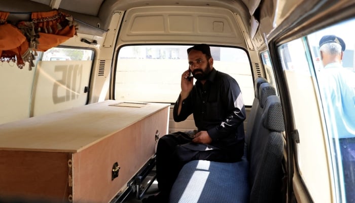 A man speaks on this mobile phone next to a coffin containing the body of newborn victim inside an ambulance following a deadly fire at the Pakistan Institute of Medical Sciences hospital in Islamabad, August 26, 2026. — Reuters
