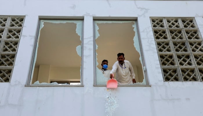 A worker removes broken pieces of a glass window after a fire broke out at the Pakistan Institute of Medical Sciences hospital in Islamabad, August 26, 2026. — Reuters