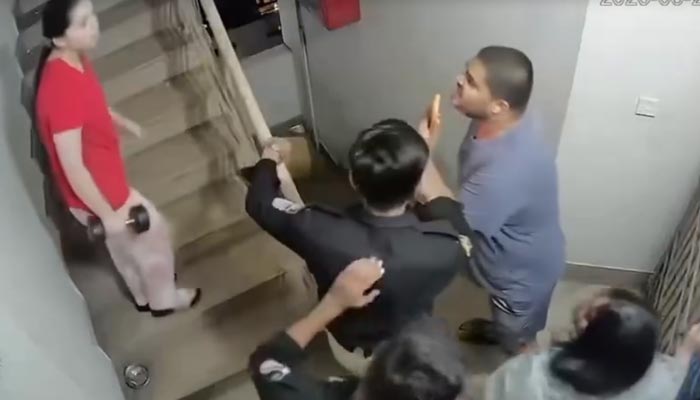 A woman with a dumbbell can be seen arguing with a man while a policeman can also be seen during the scuffle in Defence Housing Authority, Karachi. — Screengrab via CCTV/Geo News