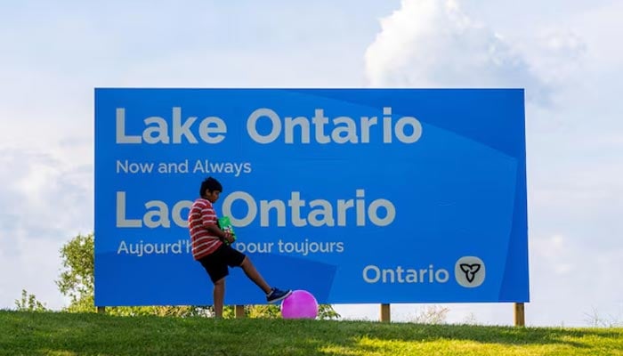 A young child plays with a ball near a sign reading Lake Ontario, Now and Always, near Grimsby, Ontario, Canada, August 29, 2026. — Reuters