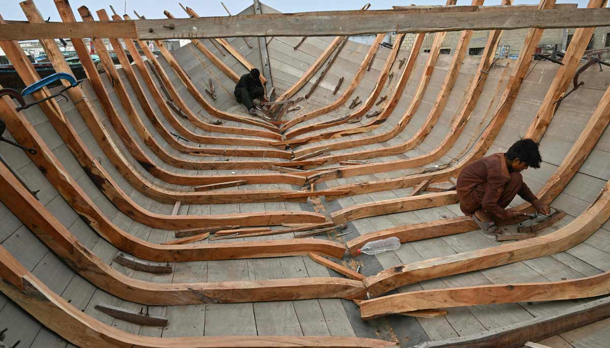 Workers building traditional wooden boats at a yard in Ibrahim Hyderi in Karachi.— AFP