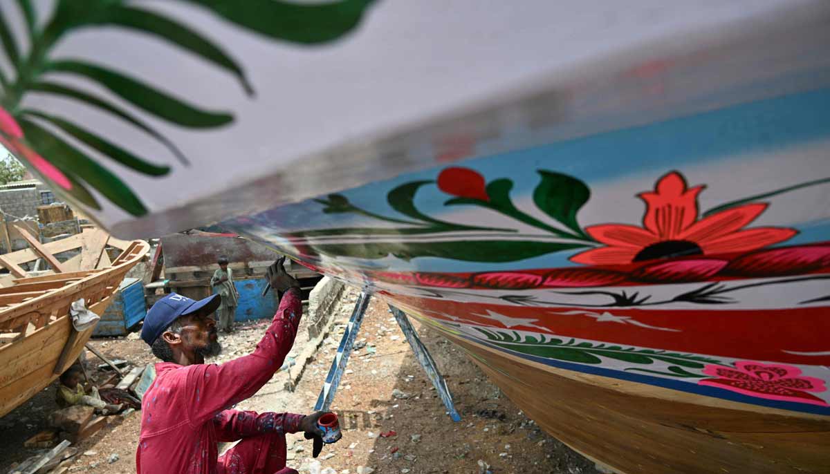 Craftsman Muhammad Ismail painting a traditional wooden boat at a yard in Ibrahim Hyderi in Karachi. — AFP