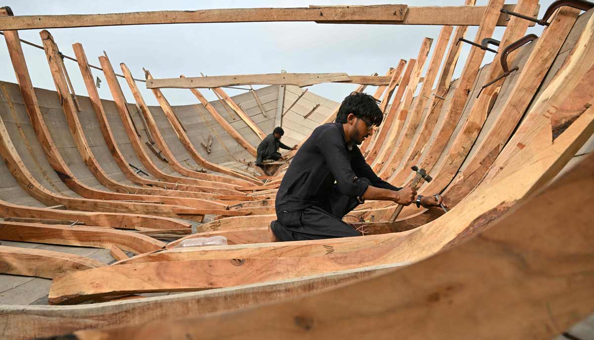 Workers building traditional wooden boats at a yard in Ibrahim Hyderi in Karachi.— AFP