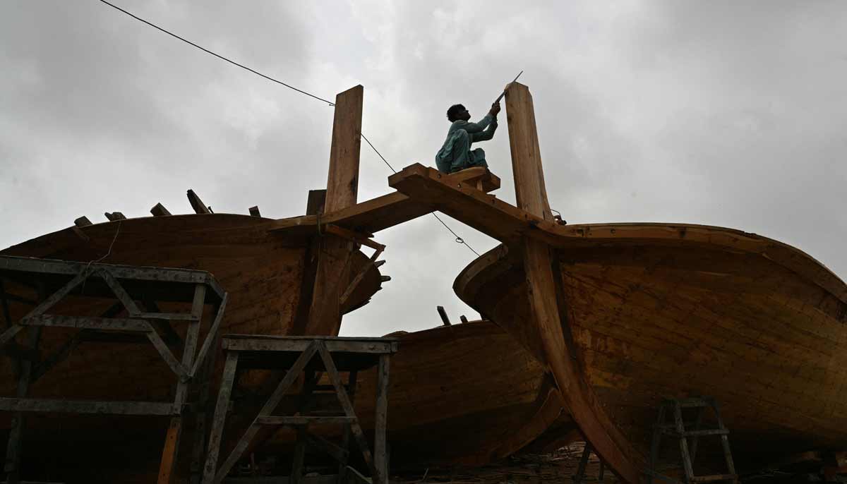 A worker building a traditional wooden boat at a yard in Ibrahim Hyderi in Karachi.— AFP