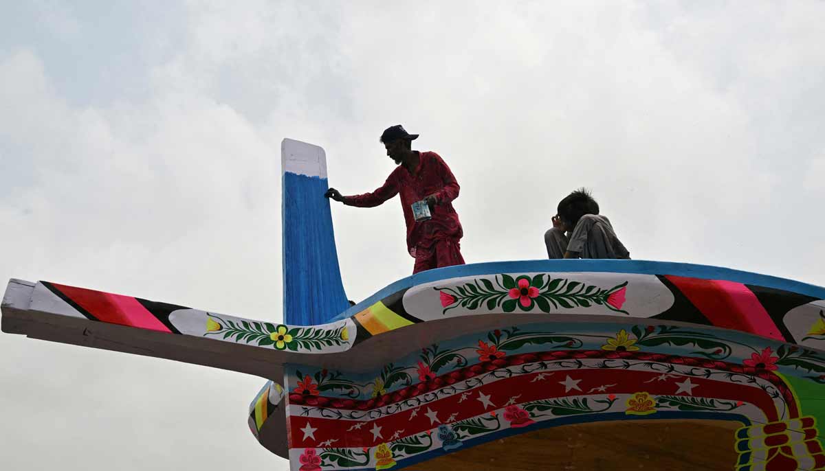 Craftsman Muhammad Ismail painting a traditional wooden boat at a yard in Ibrahim Hyderi in Karachi.