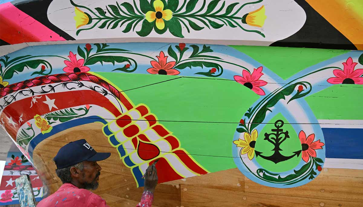Craftsman Muhammad Ismail painting a traditional wooden boat at a yard in Ibrahim Hyderi in Karachi. — AFP