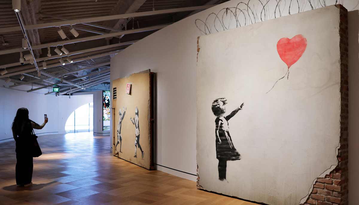 A visitor takes photos of a piece created by Banksy at the new Lucas Museum of Narrative Art during a media preview of the 300,000 square foot structure on September 2, 2026 in Los Angeles, California.— AFP