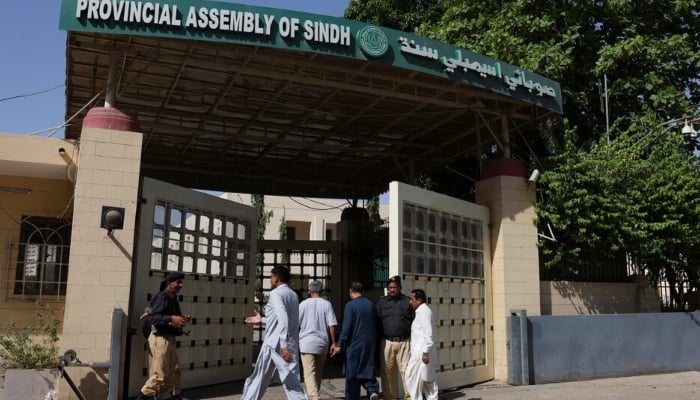 Government employees walk at the entrance gate of the Provincial Assembly of Sindh building in Karachi, March 16, 2026. — Reuters