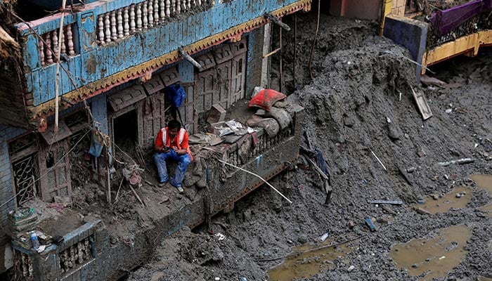 A man uses his mobile phone as he sits outside a damaged house following the deadly flash floods and mudslides in Devighat, Nuwakot district, Nepal, September 5, 2026. — Reuters