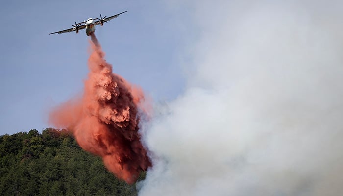 This photograph shows a Bombardier Dash 8 Q400 MR aircraft dropping fire retardant over a forest fire near Puilaurens, southwestern France, on September 5, 2026. — AFP