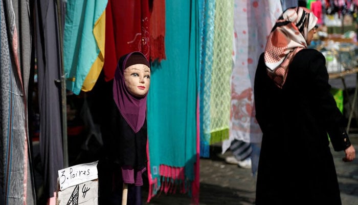 A woman walks past a mannequin wearing a hijab headscarf at a market in the Brussels district of Molenbeek, Belgium, August 14, 2016. — Reuters