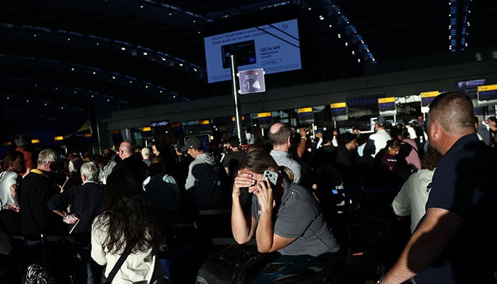 People stand with their luggage as the queue at check-in desks inside Terminal 5 of London Heathrow airport, west of London on September 8, 2026, following major disruption due an issue affecting the Nats air traffic control systems. — AFP