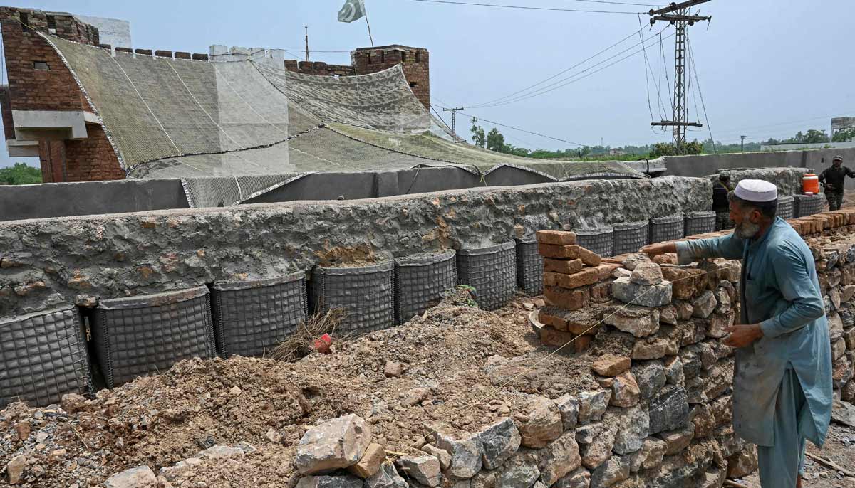 A worker is constructing a boundary wall around a police post fortified with Ukraine-style mesh barriers, as a new line of defence against militant drone and aerial attacks at Bara in Khyber Pakhtunkhwa.