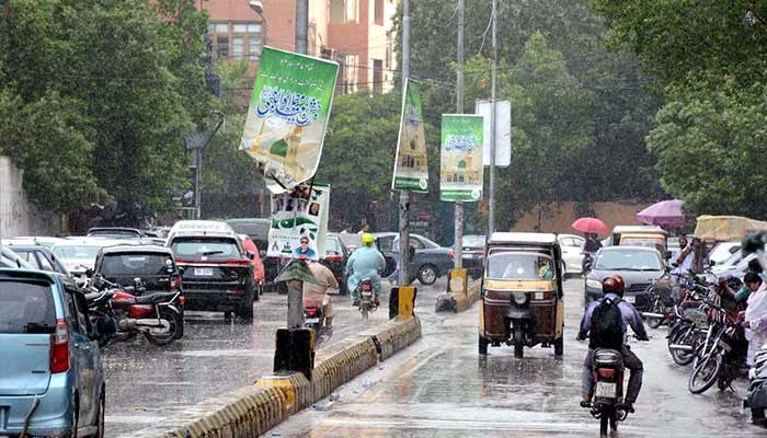 Commuters are passing through a road during the downpour of the monsoon season in the Saddar area in Karachi. — PPI