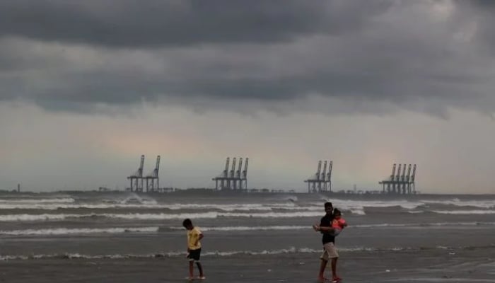 Children play with the rainbow and rain clouds in the background at Clifton Beach in Karachi. — Reuters/File