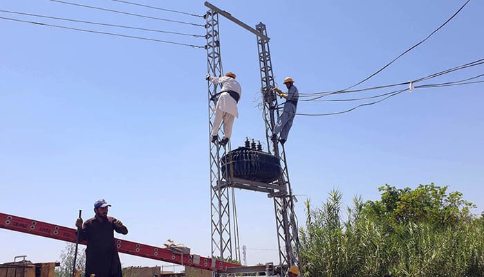 Wapda workers install a new electricity transformer at a power distribution site in Islamabads Ghouri Town on June 28, 2024. — APP