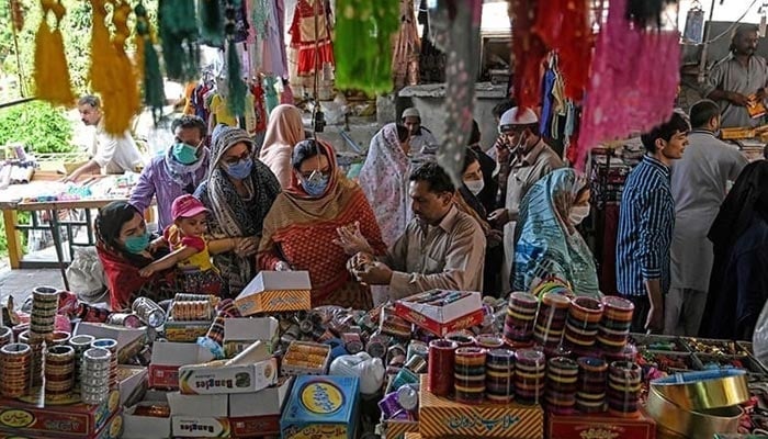 Customers shop for bangles at a market in Islamabad on May 9, 2020. — AFP