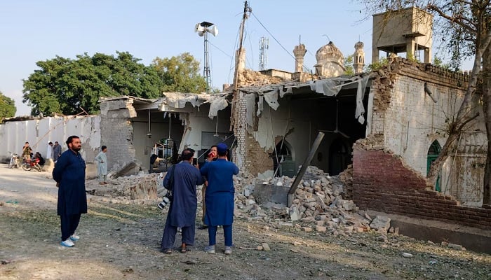 People stand near a damaged section of a police facility following a suicide attack in Kohat, Pakistan, on September 18, 2026. — Reuters