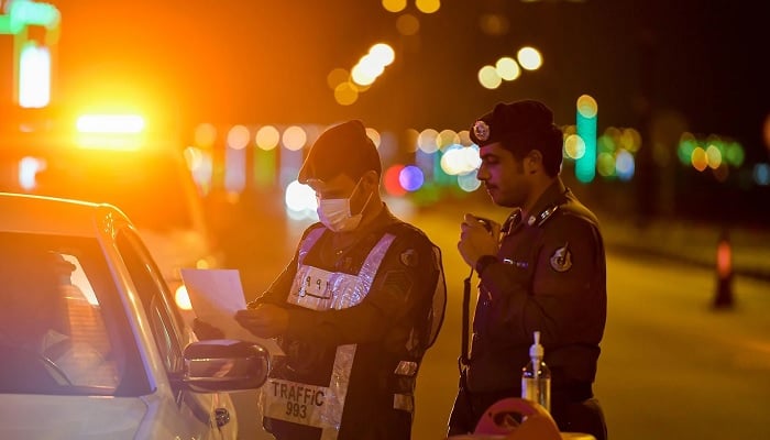 Two Saudi traffic police officers speak to a motorist while checking his documents. — Reuters/File