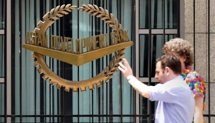 Staff members of the Asian Development Bank step out of the Manila-based lenders headquarters. — AFP/File