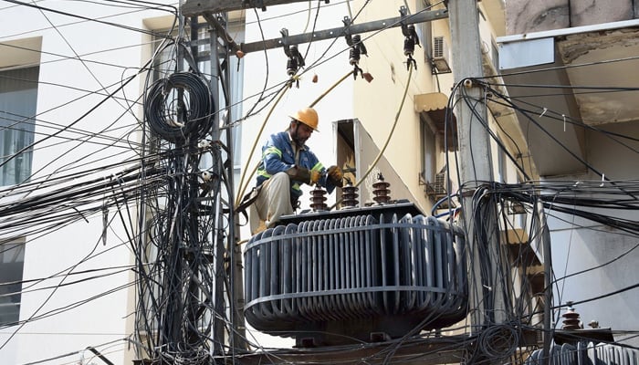 WAPDA worker fixes electricity wires on a pole at the Davis Road in Lahore on April 2, 2023. — Online