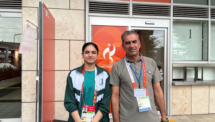 Pakistan squash player Sana Bahadar and her father Sher Bahadar pose for a picture outside the Nagoya Kinjo-Futo Arena. — Reuters